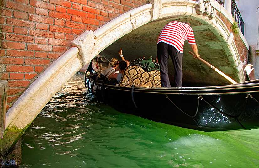 Der Gondoliere muss sich bei der Brückedurchfahrt bücken Gondelfahrt durch die Brücken von Venedig